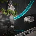 Modern Water Fountain Featuring Blue Curved Design with Flowing Water and Natural Rocks Pine Tree
