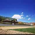 Scenic Garden Landscape with Blue Sky White Clouds Green Lawn Wooden Building and Distant Mountains