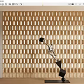 Dynamic Metallic Sculpture With Geometric Cubes On Black Base Against Light Wooden Grid Wall