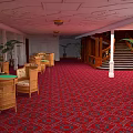 Cartoon Scene of Elegant Indoor Hall with Red Carpet Wicker Chairs Palm Plants and Staircase