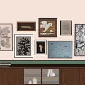 Gallery Wall With Various Framed Artworks Different Styles Wooden Cabinet And Books On Top