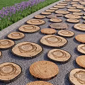 Natural Wooden Log Slice Stepping Stones On Gravel Ground With Purple Flowers And Grass
