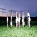 Outdoor Pillar Lights With Natural Wood Design Illuminating Green Lawn At Dusk