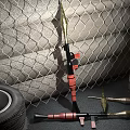 Spear Weapon Displayed Near Metal Mesh Background With Stacked Tire And Wooden Crate
