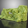 Green Natural Stone Decorative Piece With Textured Surface And Hollow Design On Reflective Base