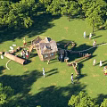 Outdoor Kids Playground With Wooden Play Structures And Green Trees On Grass