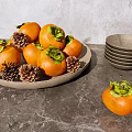 Fresh Persimmons in Brown Plate with Pine Cones Bowls and Clear Cups on Gray Tabletop