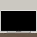 Black TV With Silver Stand On Wooden Floor Against Light Colored Wall
