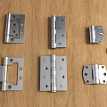 Various Metal Hinges And Small Screws On Wooden Table Top