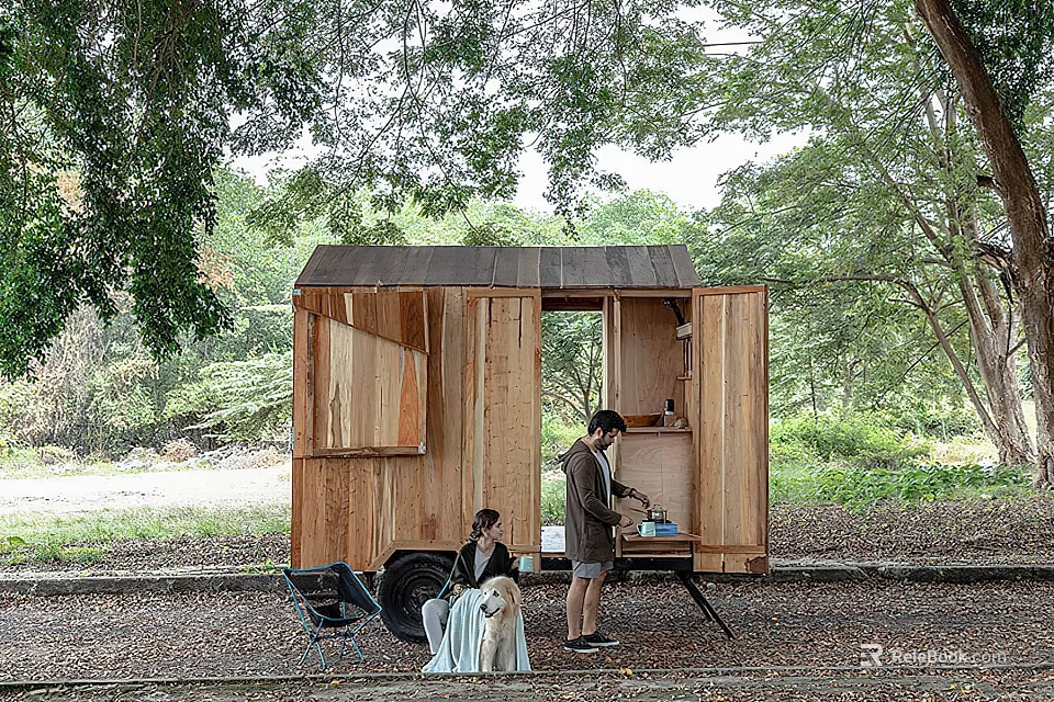 Wooden Trailer Style Cabin Surrounded by Trees with Two People Resting Outside 3d model 