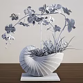 White Shell Shaped Vase With Pink Orchids Green Plants And Blue Flowers On Wooden Table