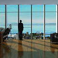 Spacious Office Interior With Large Windows Sea View Cityscape Wooden Flooring Person Standing By Window