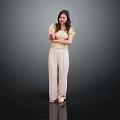 Woman in yellow top and beige pants standing with crossed arms against dark background
