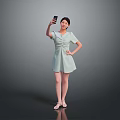Woman Posing in Light Green Dress Taking Selfie with Mobile Phone Against Gray Background
