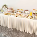 Elegant Dessert Table With White Tablecloth Decorative Flowers And Assorted Sweet Treats