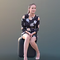 Young Woman In Floral Dress Sitting On Black Cylindrical Stool Against Dark Background