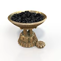 Golden Decorative Bowl With Intricate Base Holding Black Granules And Small Gear