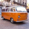 Orange Vintage Volkswagen Van Parked On Stone Pavement In Historic Town Square