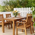 Wooden Dining Chairs With Dining Table Yellow Flowers And White Picket Fence In Garden