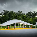 White Pergola With Benches And Yellow Pathway In Green Lawn With Trees And People Gathering