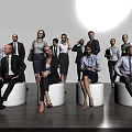 Group of Business Professionals Standing and Sitting in Office With Gray Wall and Wooden Floor