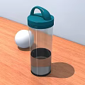 Transparent Cup With Green Lid And White Ball On Wooden Table Surface