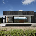 Modern Detached House Featuring Black Exterior Large Glass Windows Sunset Glow and Illuminated Interior