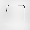 Modern Black Curved Arm Wall Lamp with Transparent Filament Bulb Mounted on White Wall