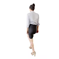 A woman wearing white shirt and black leather skirt standing sideways in beige high heels
