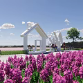 Scenic Post Station Amid Pink Flower Field Featuring White Building Tree Sculptures And Blue Sky