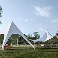 White Outdoor Tents on Green Grass with Trees Cloudy Sky and Wooden Tables