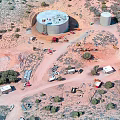 Desert Industrial Facility Aerial View With Two Large Cylindrical Tanks Vehicles Small Buildings and Vegetation