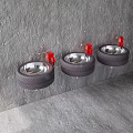 Three Black Tire Repurposed Washbasins With Red Faucets And Metal Brackets On Gray Textured Wall