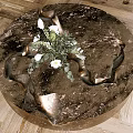 Round Metallic Coffee Table With Sculptural Indents And White Flower Arrangement On Wooden Floor