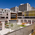 Vibrant Commercial Street Featuring Multi Story Buildings Glass Facades Plaza Greenery And Outdoor Seating