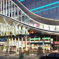 Modern Architectural Landscape With Glass Facade Blue Lighting Storefronts And Urban Pedestrian View