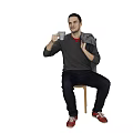 Man sitting on chair holding white cup wearing gray sweater red shirt red shoes