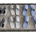 Grey And Blue Slippers With Sneakers Placed On Woven Mat At Home