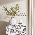 White Textured Vase With Green Branch Greenery On Marble Cabinet With Small Lamp