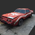 Red Vintage Car with White Graphics Damaged Front End Parked on Cracked Concrete Surface