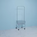 Metal Cart With Wire Basket And Wheels Against Light Blue Wall On White Marble Floor