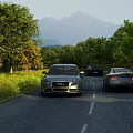 Cars Driving On Scenic Road With Green Trees And Distant Mountains
