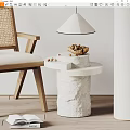Textured White Stone Side Table with Rattan Chair Bowl of Nuts and Table Lamp