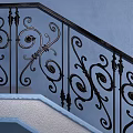 Ornate Staircase With Black Iron Railings Blue Wall Green Plant Black Vases And Pebble Decor