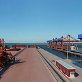 Spacious Industrial Plant Area With Red Cranes Blue Sky Water View And Rail Tracks