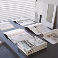 Open and stacked magazines placed on dark table with blinds in background