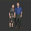 A Man In Blue Shirt Standing With Woman In Floral Dark Dress Against Gray Background