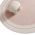 Round Pink Rug With White Black Dotted Border And Small White Pillow On Top