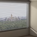 Window Blinds Filtering Sunlight In Room With City And Green Park View