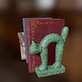 Colorful Stacked Books With Green Cat Shaped Bookend And Various Covers